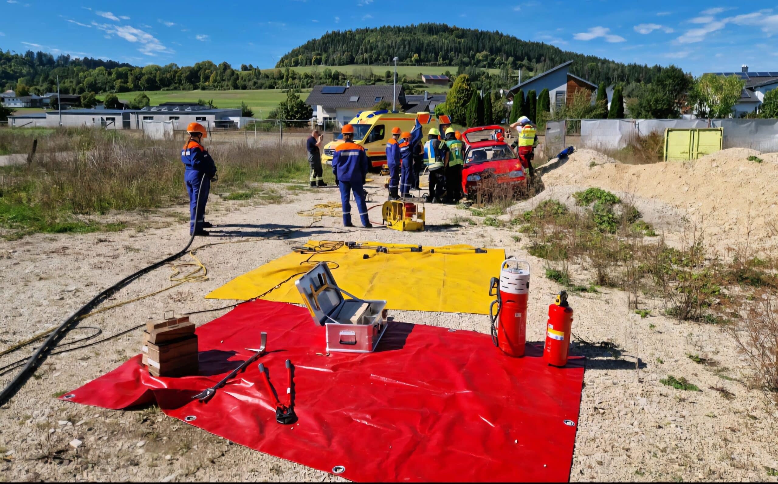 Mehrere Werkzeuge von der freiwilligen Feuerwehr liegen auf Roten und Gelben lagen. Mehrere Personen der Freiwilligen Feuerwehr stehen im Hintergrund