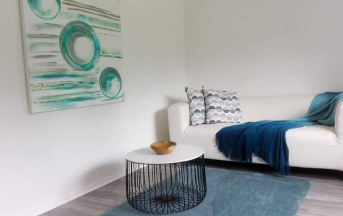 Weißes Sofa vor einem runden modernen Tisch und ein Kunstvollen Gemälde an der Wand