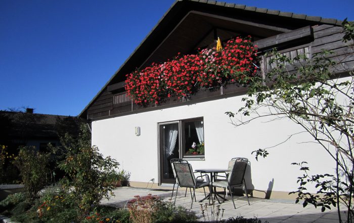 Außenterasse mit Gartenstühle und Gartentisch hinter einem Haus